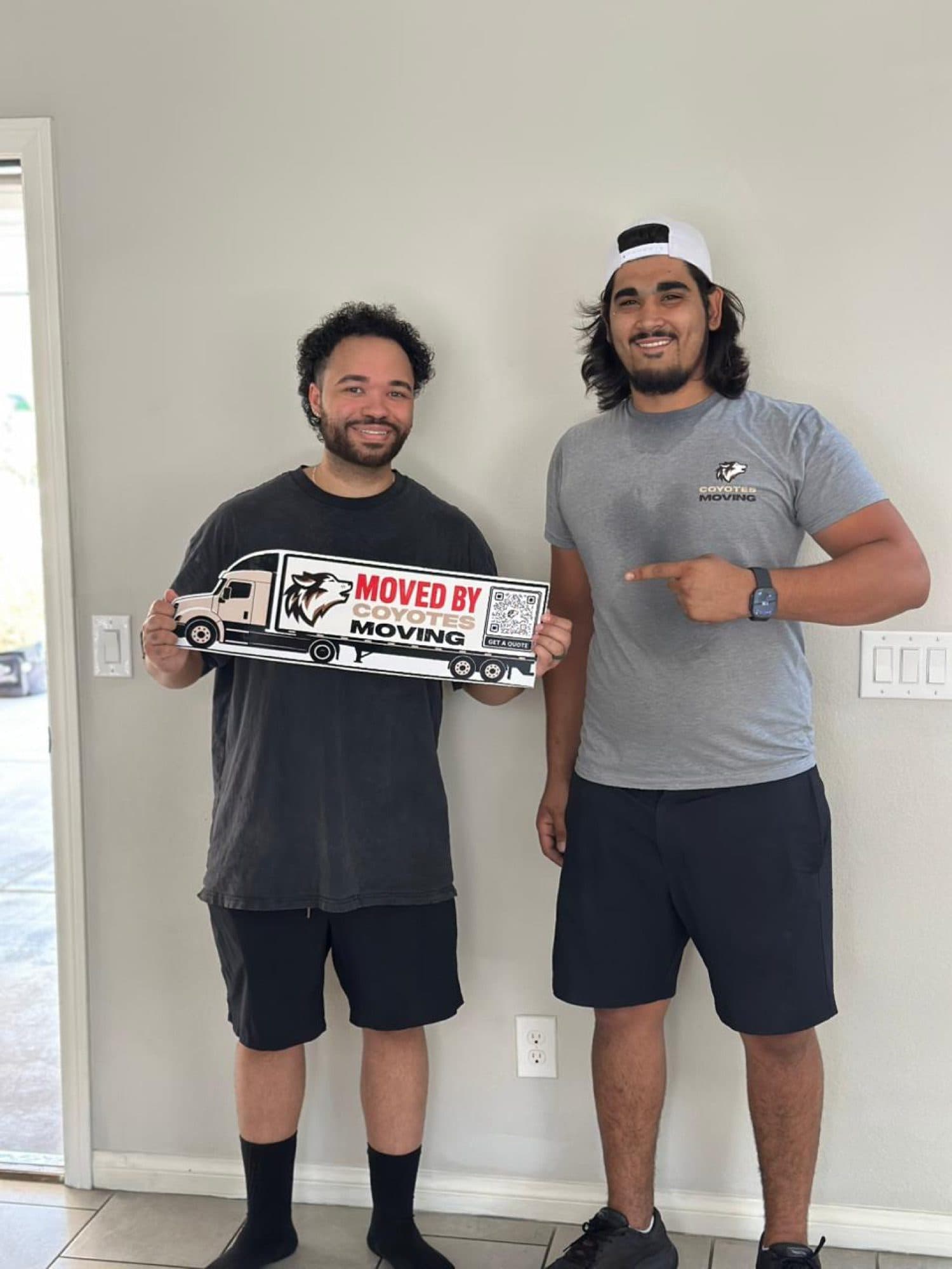 Coyotes Moving customers holding the "Moved By Coyotes Moving" sign