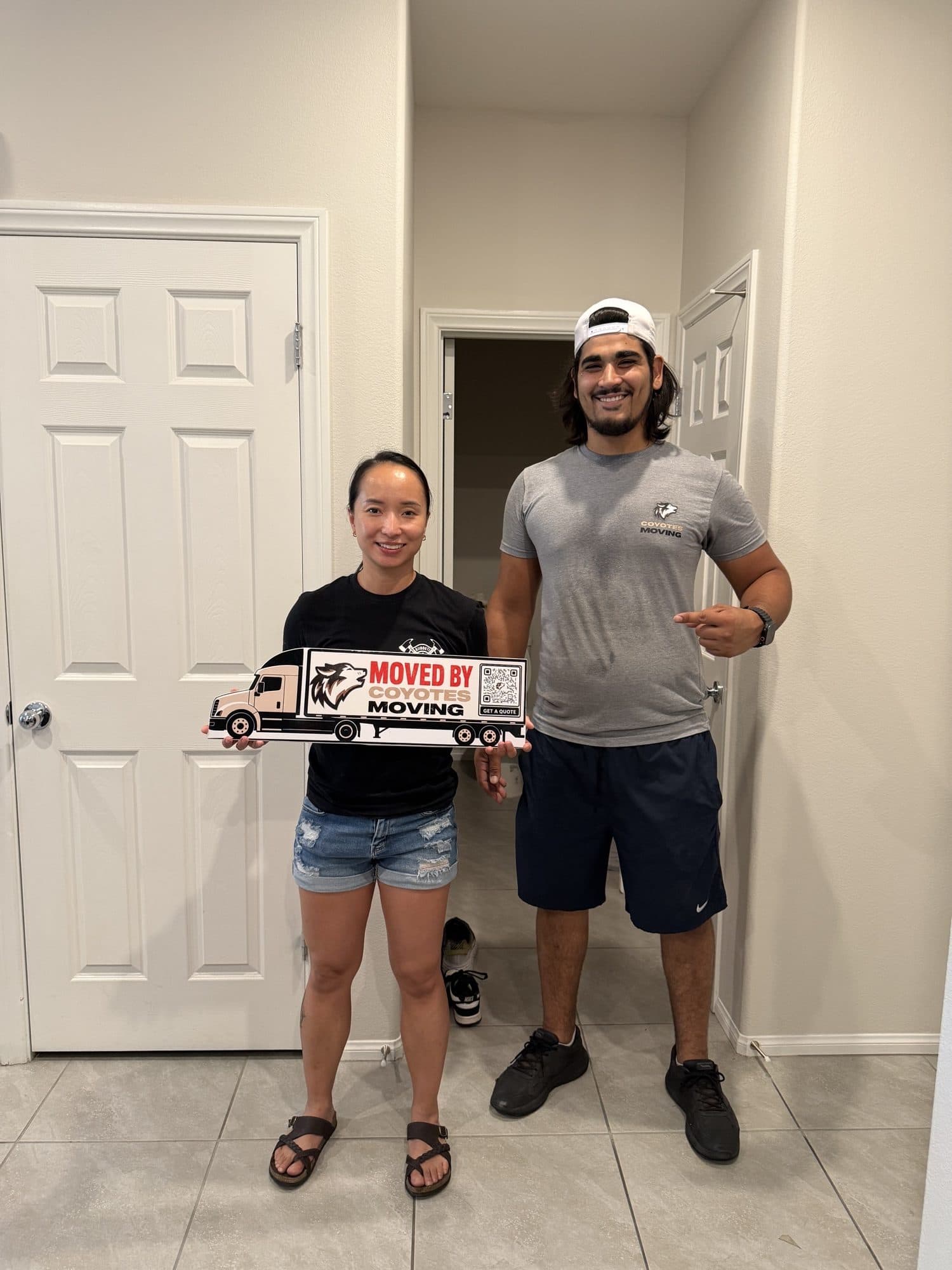 Coyotes Moving customers holding the "Moved By Coyotes Moving" sign