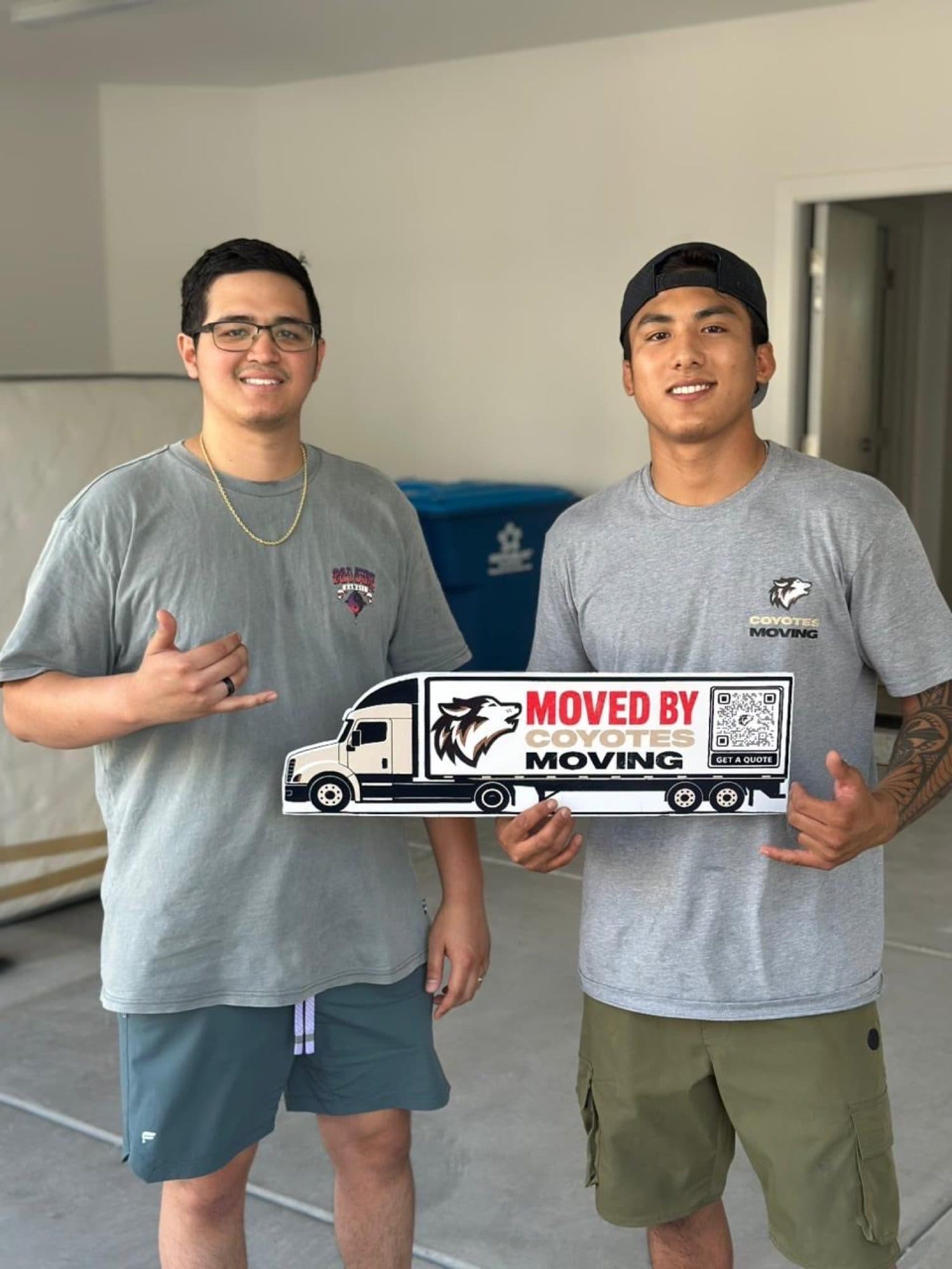 Coyotes Moving customers holding the "Moved By Coyotes Moving" sign