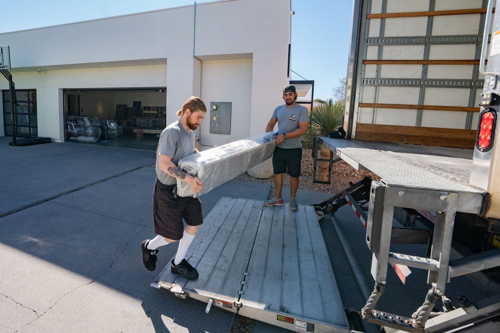 Coyotes Moving crew loading a wrapped piece of furniture up a truck ramp for a full-service interstate move to California