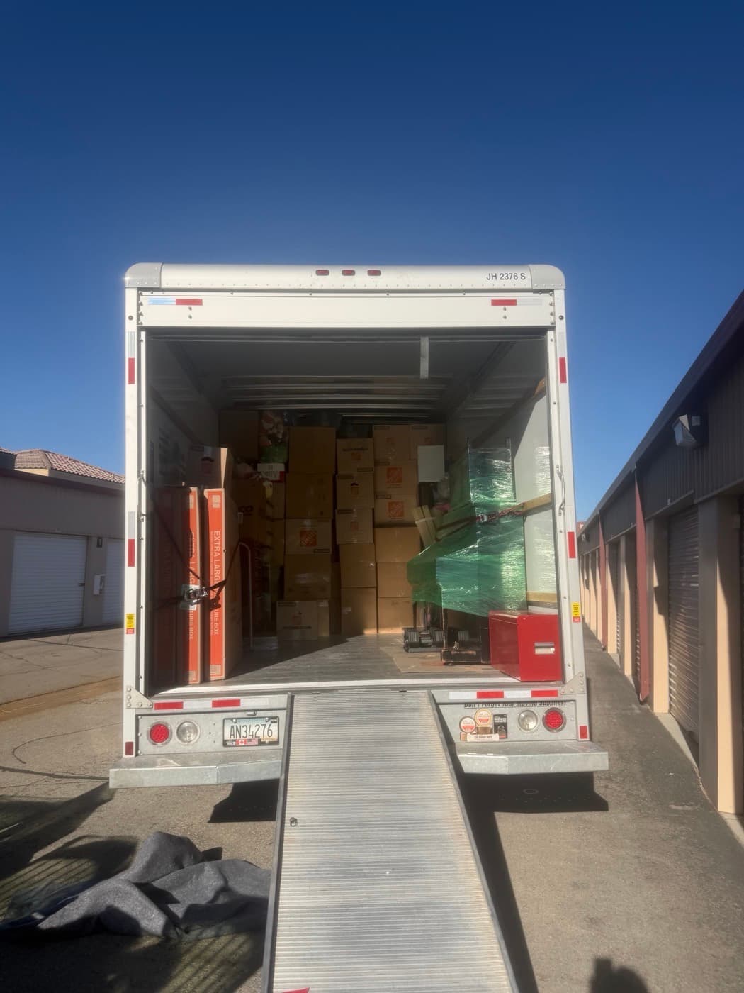 Coyotes Moving crew carrying a wrapped mattress out to a rental truck